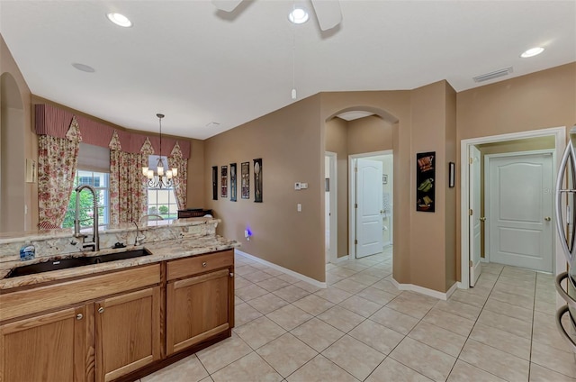 kitchen with light tile patterned flooring, decorative light fixtures, sink, ceiling fan, and light stone counters