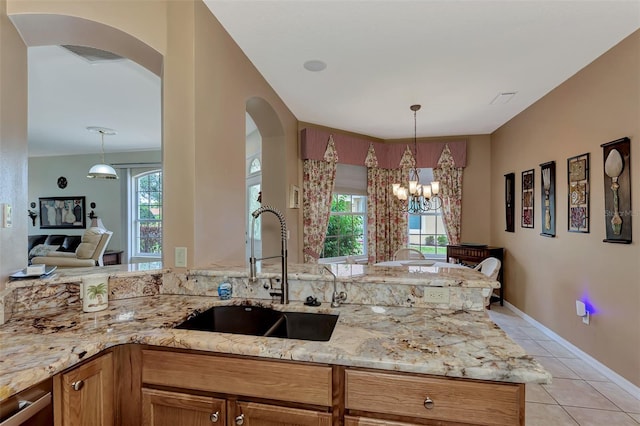 kitchen featuring light stone counters, sink, hanging light fixtures, and light tile patterned floors