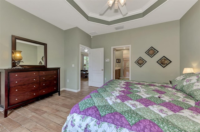 bedroom with ensuite bath, ornamental molding, a raised ceiling, and ceiling fan