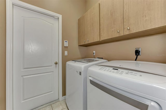 washroom featuring independent washer and dryer, light tile patterned floors, and cabinets