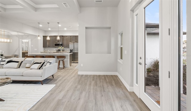 living room featuring beam ceiling, sink, and light hardwood / wood-style floors