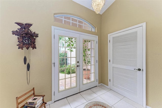 doorway to outside with french doors, vaulted ceiling, a notable chandelier, and light tile patterned flooring