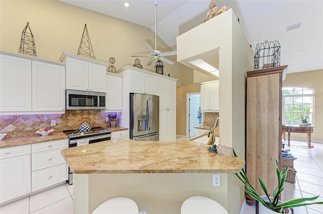 kitchen featuring white cabinetry, sink, backsplash, a kitchen bar, and appliances with stainless steel finishes