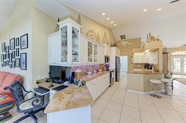 kitchen with backsplash, white cabinets, ceiling fan, light tile patterned floors, and stainless steel appliances