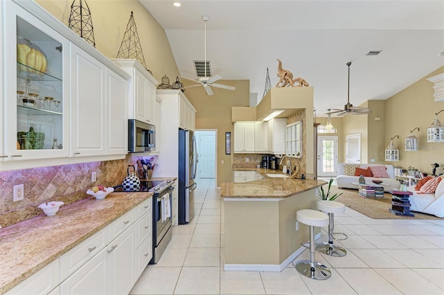 kitchen featuring decorative backsplash, appliances with stainless steel finishes, light stone counters, white cabinetry, and light tile patterned flooring