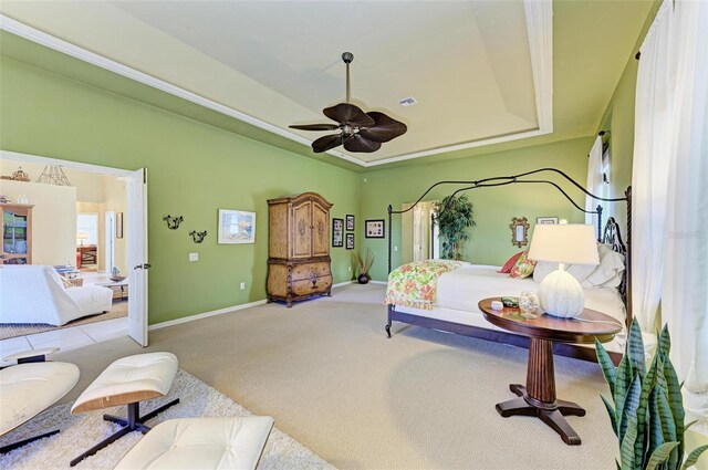 bedroom with ceiling fan, light carpet, and a tray ceiling