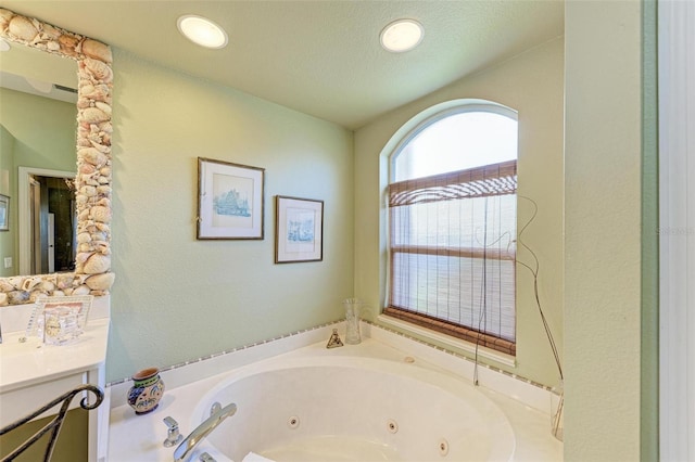 bathroom with a textured ceiling, vanity, and a tub