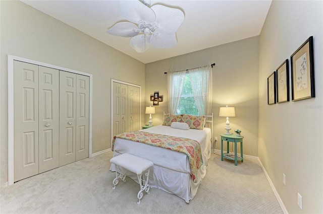 carpeted bedroom featuring multiple closets and ceiling fan