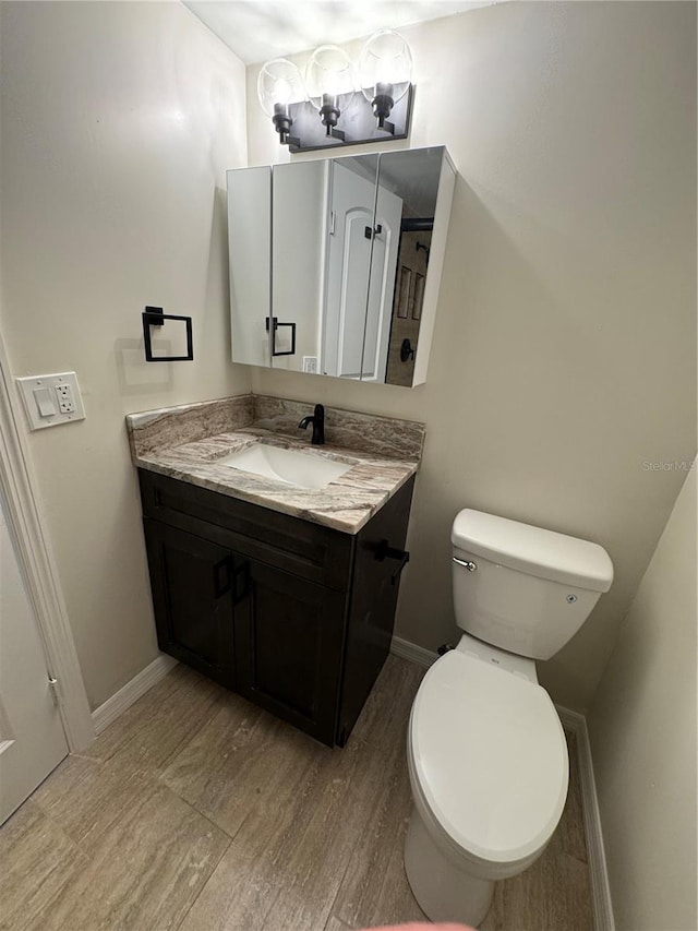 bathroom with vanity, wood-type flooring, and toilet