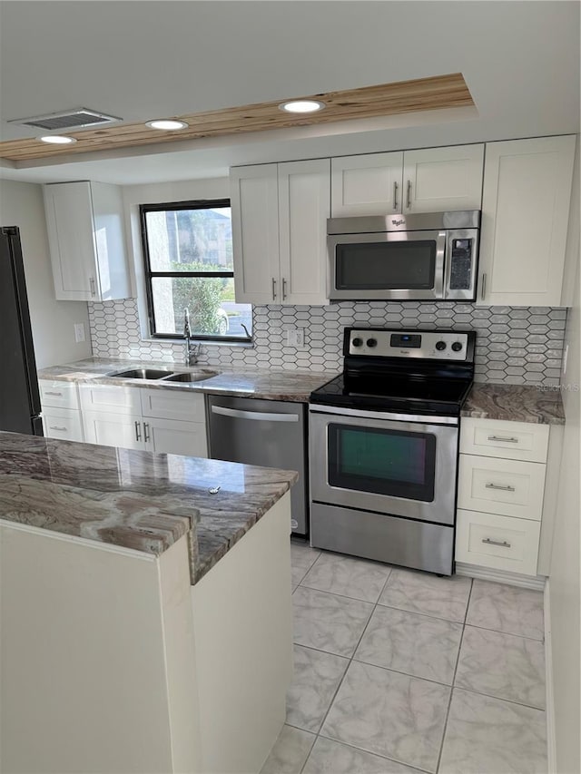 kitchen with white cabinets, decorative backsplash, stainless steel appliances, and sink