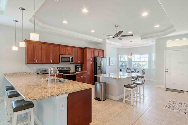 kitchen with decorative light fixtures, a raised ceiling, stainless steel appliances, and a breakfast bar area