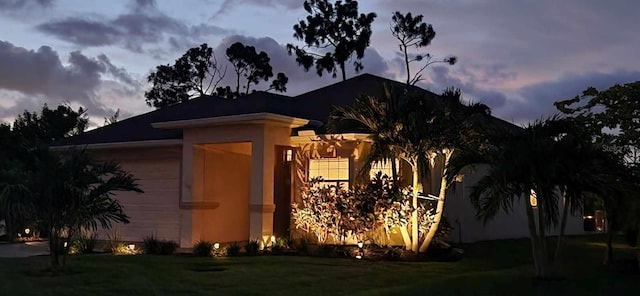 property exterior at dusk with a garage and a lawn