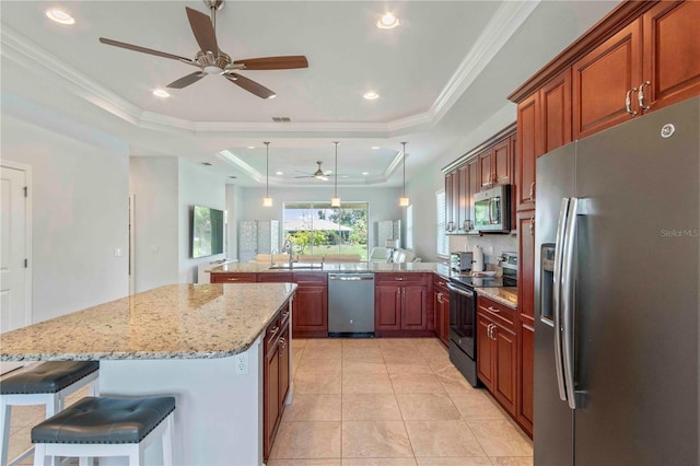 kitchen featuring a kitchen bar, kitchen peninsula, stainless steel appliances, a raised ceiling, and pendant lighting