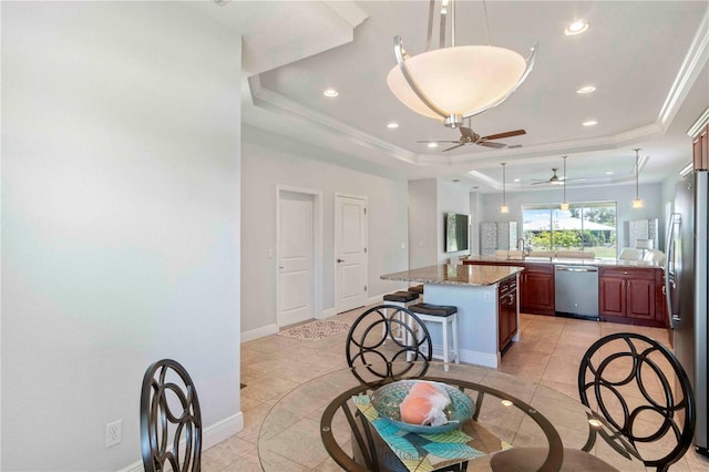 kitchen featuring light stone countertops, appliances with stainless steel finishes, a tray ceiling, a center island, and light tile patterned flooring