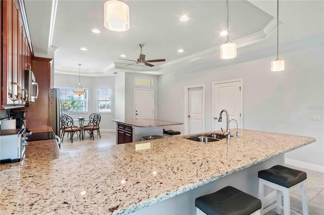 kitchen with light stone countertops, ceiling fan, sink, and pendant lighting