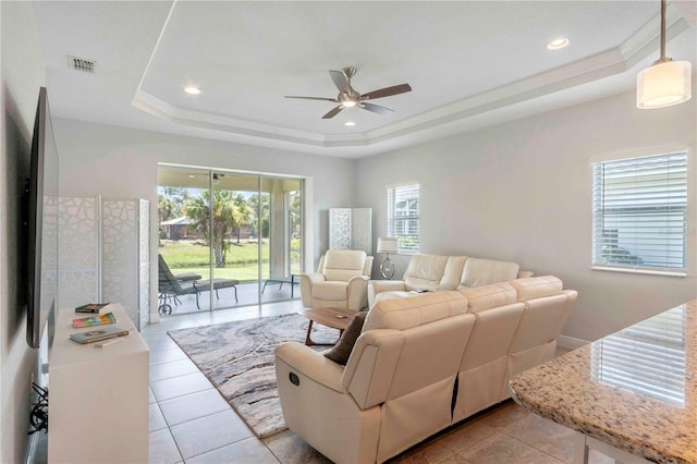 tiled living room featuring a raised ceiling, ceiling fan, and ornamental molding