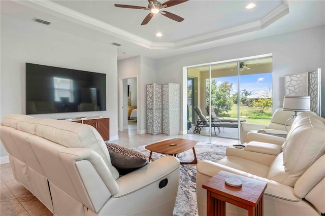 tiled living room with ceiling fan and a raised ceiling