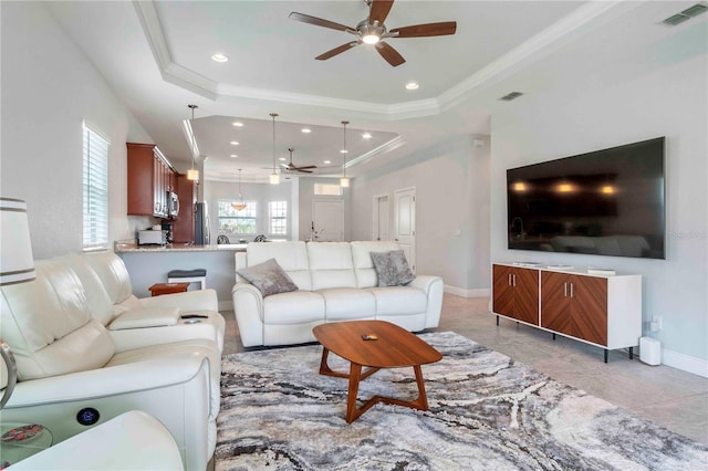 living room with a raised ceiling, ceiling fan, and crown molding