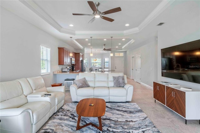 living room with ceiling fan, a raised ceiling, and crown molding