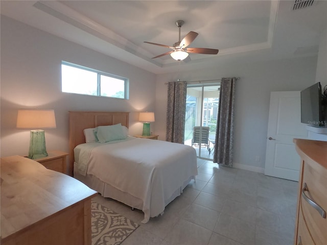 tiled bedroom with access to exterior, ceiling fan, and a raised ceiling