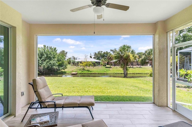 sunroom featuring ceiling fan, a healthy amount of sunlight, and a water view