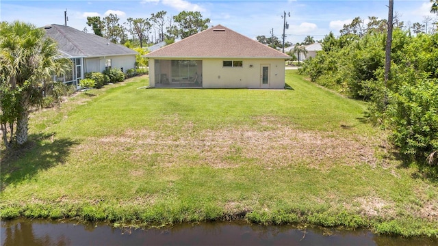 back of house featuring a lawn, a sunroom, and a water view