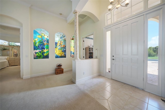 carpeted foyer with decorative columns, crown molding, and plenty of natural light