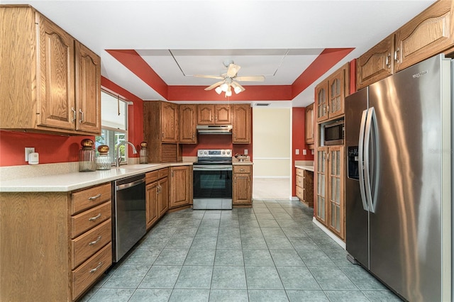 kitchen featuring a tray ceiling, ceiling fan, sink, and stainless steel appliances