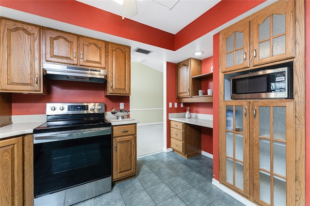 kitchen with built in desk, stainless steel appliances, ceiling fan, and dark tile patterned floors