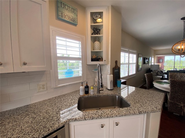 kitchen featuring light stone countertops, sink, backsplash, and white cabinetry