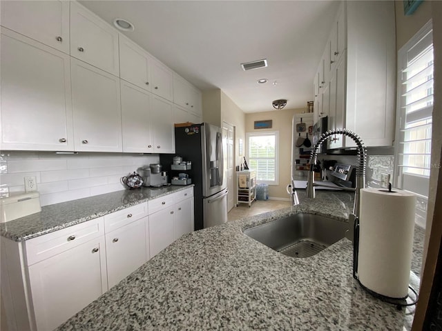 kitchen featuring light stone counters, sink, white cabinets, and tasteful backsplash