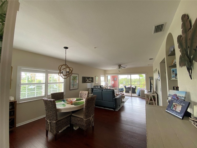 dining area featuring ceiling fan with notable chandelier and dark wood-type flooring