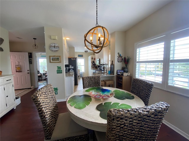 dining area with a chandelier, sink, and dark hardwood / wood-style floors