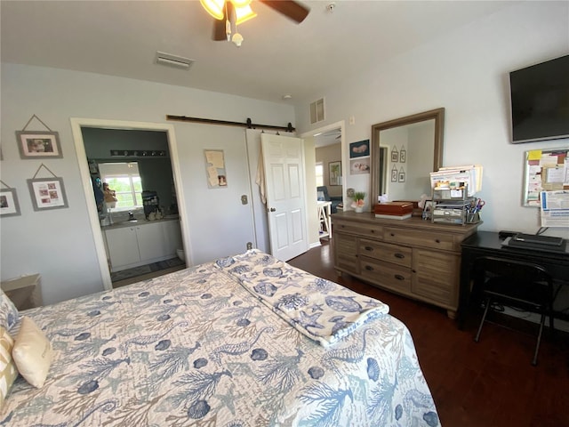 bedroom featuring a barn door, connected bathroom, dark wood-type flooring, and ceiling fan