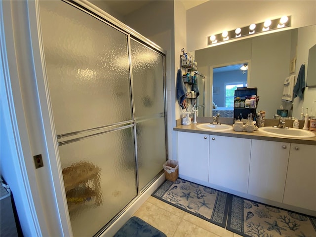 bathroom featuring a shower with door, dual sinks, tile flooring, and oversized vanity