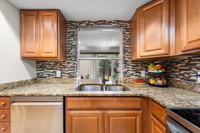 kitchen featuring stainless steel dishwasher, light stone counters, sink, and tasteful backsplash