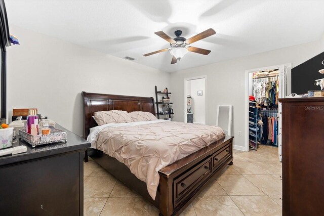 tiled bedroom featuring ceiling fan, a spacious closet, and a closet