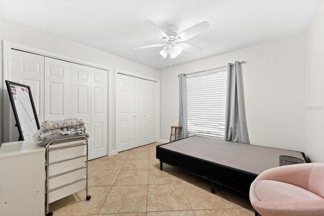 bedroom with light tile patterned floors, two closets, and ceiling fan