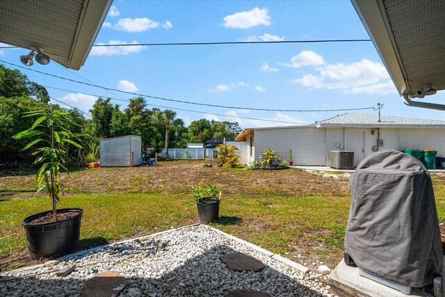 view of yard featuring central AC unit and a storage shed