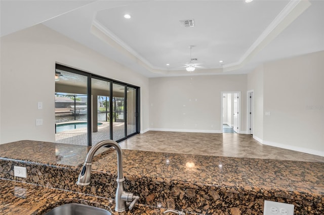 kitchen with a tray ceiling, ceiling fan, ornamental molding, and sink