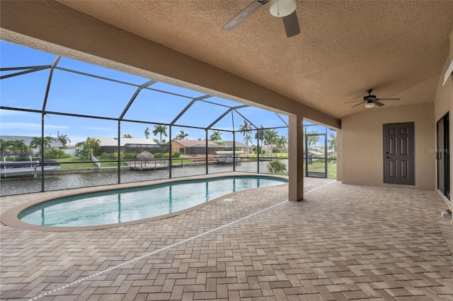 view of pool featuring ceiling fan, a patio area, a water view, and glass enclosure