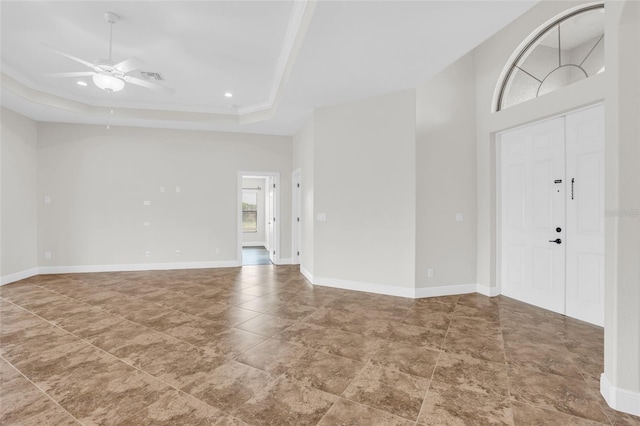 entryway with ceiling fan, a high ceiling, and a tray ceiling