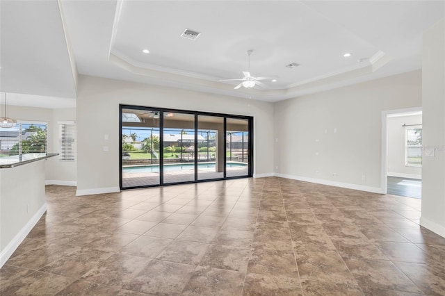 spare room with ceiling fan, a healthy amount of sunlight, and a raised ceiling