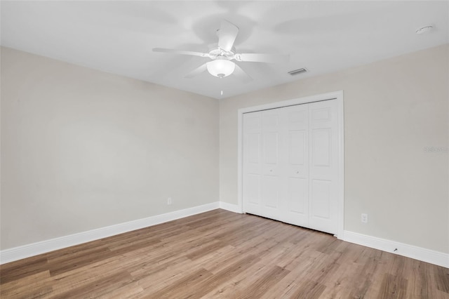 unfurnished bedroom featuring ceiling fan, a closet, and light wood-type flooring