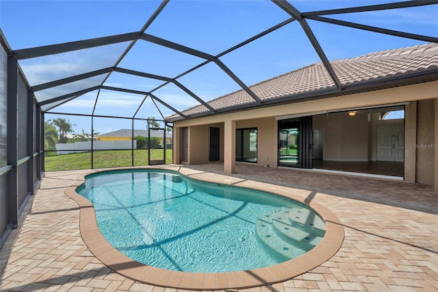 view of swimming pool featuring a lanai, a patio area, and a lawn