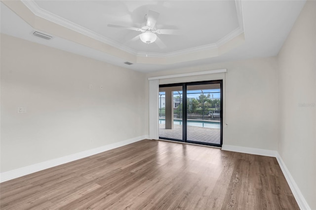 unfurnished room featuring a tray ceiling, ceiling fan, ornamental molding, and hardwood / wood-style flooring