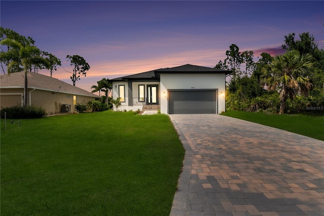 view of front of home featuring a yard, cooling unit, and a garage