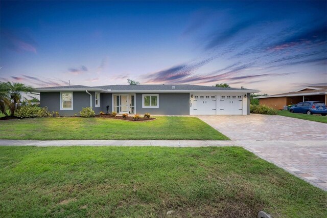 single story home with a garage and a lawn