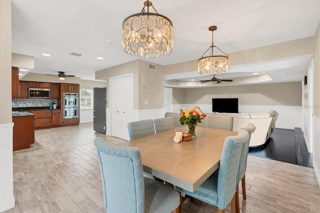 dining area with ceiling fan with notable chandelier and light hardwood / wood-style floors