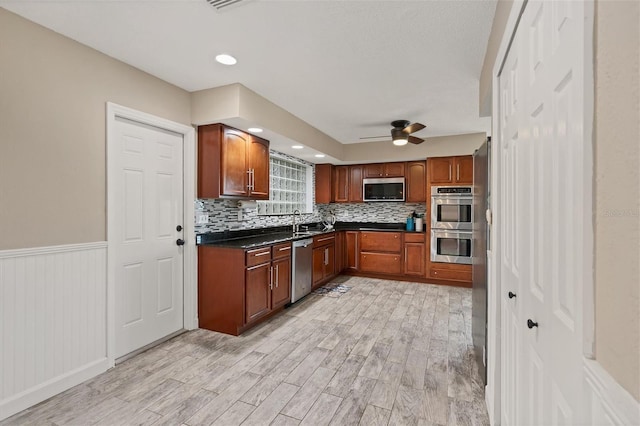 kitchen with sink, light hardwood / wood-style flooring, ceiling fan, appliances with stainless steel finishes, and tasteful backsplash